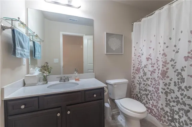 a bathroom with a granite countertop toilet sink and mirror
