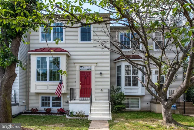 a front view of a house with a garden and trees