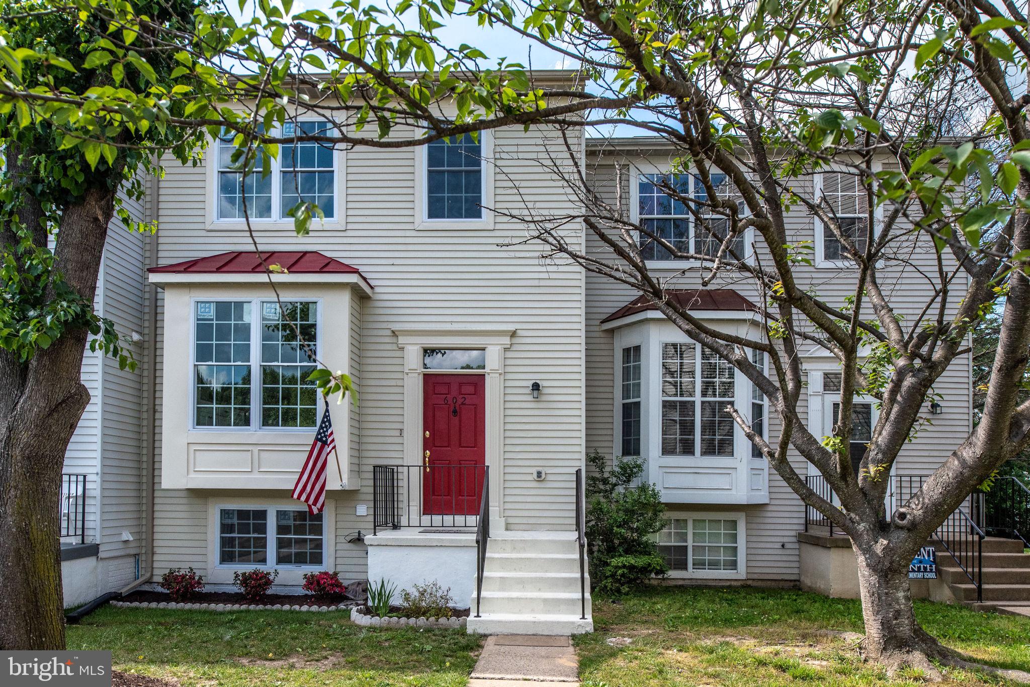 a front view of a house with a garden and trees