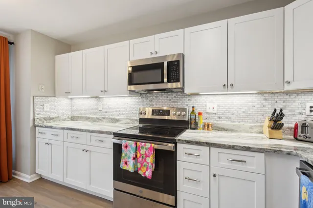 a kitchen with granite countertop white cabinets sink and stainless steel appliances