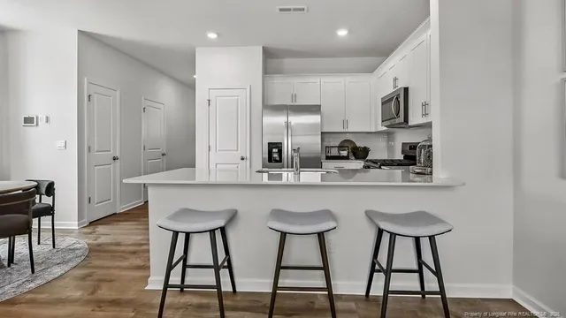 a kitchen with stainless steel appliances a table chairs refrigerator and sink
