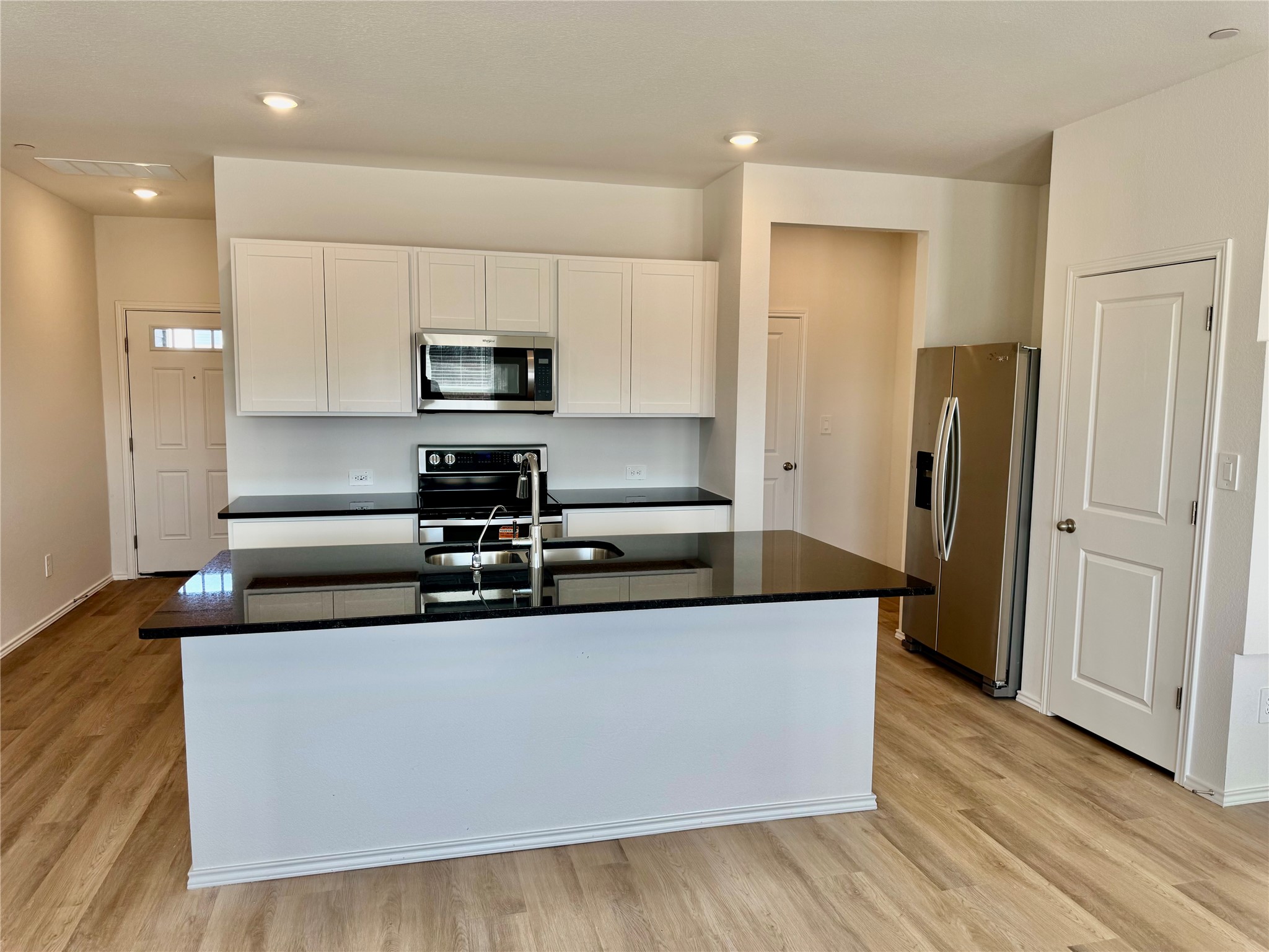 104 Calcite Road, Unit 4 Kyle, TX 78640 - Photo 2 of 7 Kitchen with white cabinetry, appliances with stainless steel finishes, a center island with sink, light wood-type flooring, and recessed lighting