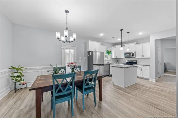 a view of a dining room and livingroom with furniture wooden floor a chandelier