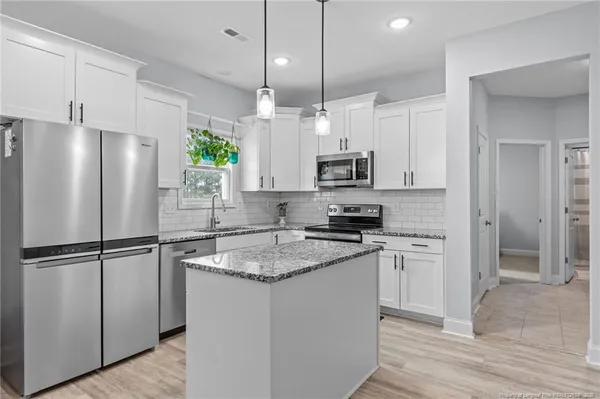 a kitchen with stainless steel appliances granite countertop a refrigerator a sink a stove a microwave and wooden cabinets