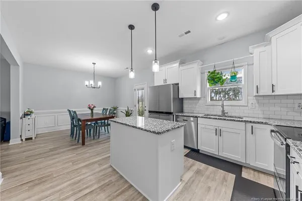 a open kitchen with stainless steel appliances granite countertop a stove and a wooden floors