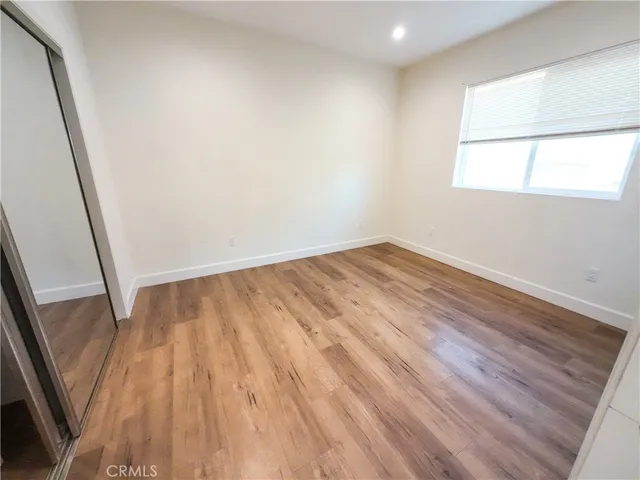 a view of empty room with wooden floor and window