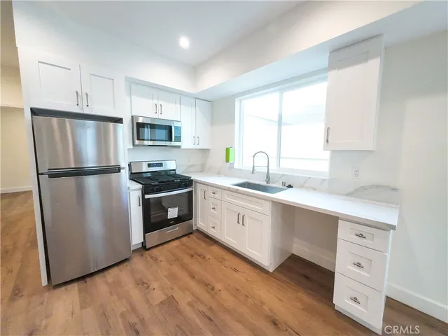 a kitchen with granite countertop a refrigerator stove top oven and sink