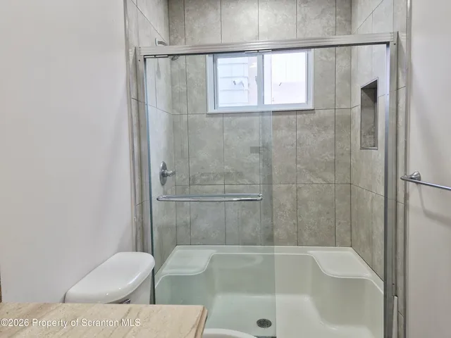 a view of a livingroom with wooden floor a ceiling fan and windows