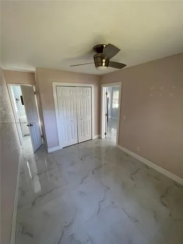 an empty room with a ceiling fan and window