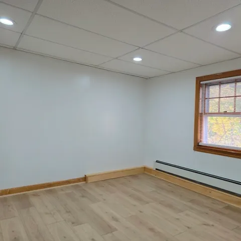 an empty room with wooden floor and windows with curtains