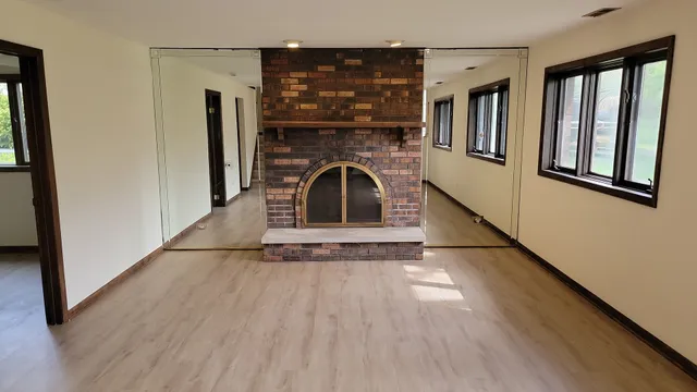 a view of a livingroom with wooden floor and a fireplace
