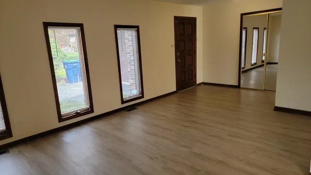 a view of an empty room with wooden floor and a window