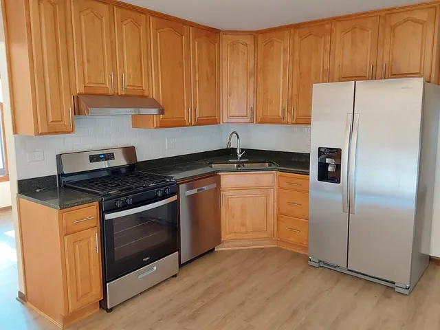 a kitchen with granite countertop wooden cabinets and stainless steel appliances