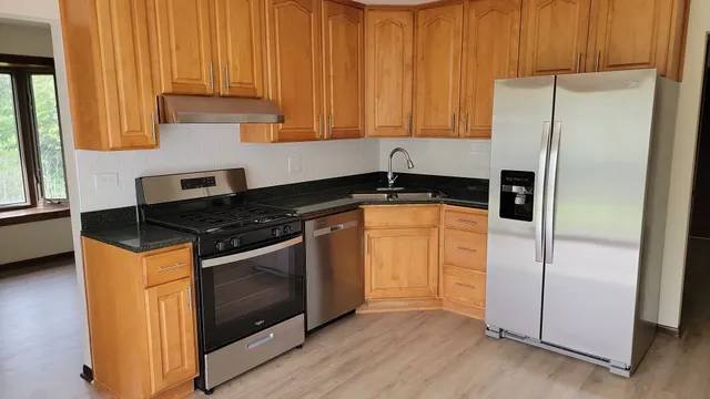 a kitchen with stainless steel appliances granite countertop a refrigerator and a sink