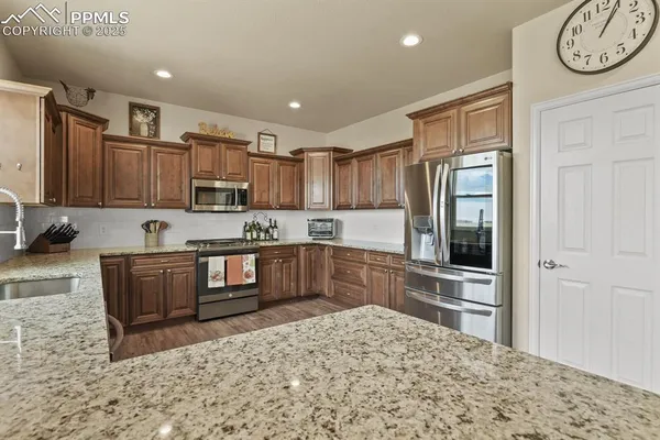 a kitchen with stainless steel appliances granite countertop a refrigerator and a stove top oven