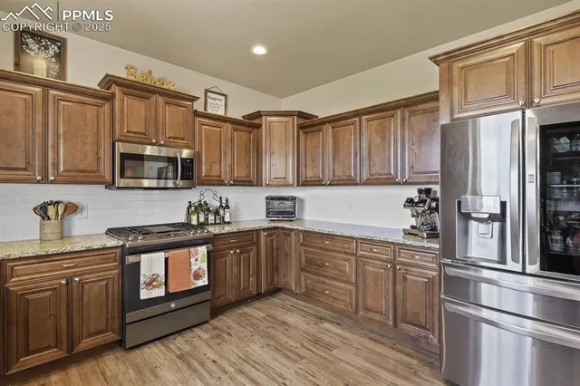 a kitchen with stainless steel appliances granite countertop a refrigerator a stove top oven a sink and dishwasher with wooden floor