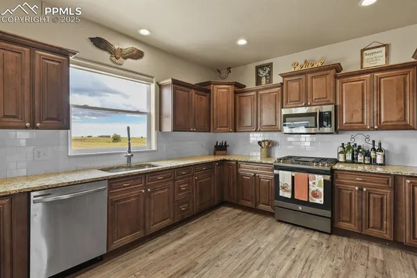 a kitchen with stainless steel appliances granite countertop wooden cabinets a sink and dishwasher a stove top oven with wooden floor