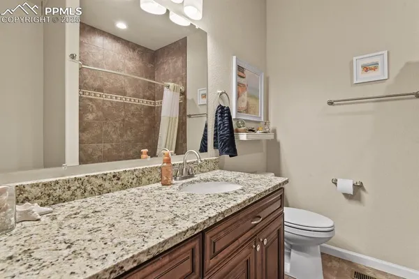 a bathroom with a granite countertop sink toilet and shower