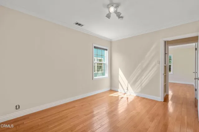 a view of empty room with wooden floor and fan