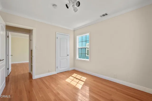 a view of empty room with wooden floor and fan