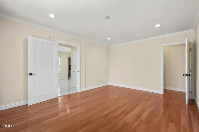 a view of an empty room with wooden floor and closet