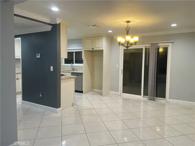an empty room with kitchen and chandelier fan