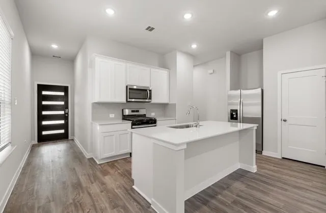 a kitchen with a sink a counter top space stainless steel appliances and cabinets