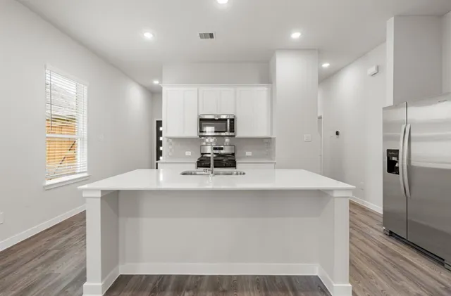 a kitchen with kitchen island a sink stainless steel appliances and cabinets