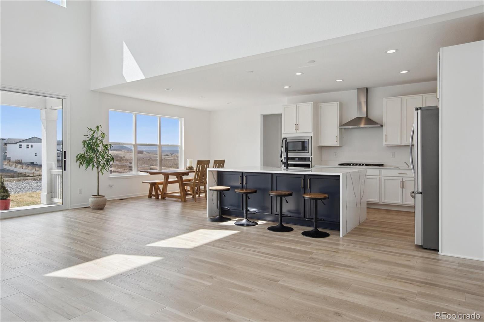741 Simmental Loop Castle Rock, CO 80104 - Photo 9 of 50 a living room with stainless steel appliances kitchen island granite countertop a large kitchen island a stove a refrigerator a sink and a dining table with wooden floor