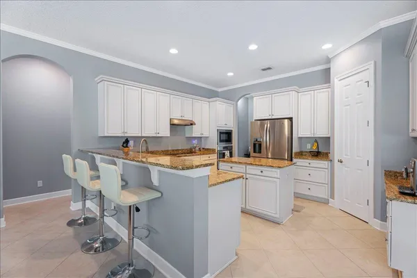 a kitchen with stainless steel appliances granite countertop a refrigerator sink stove and white cabinets