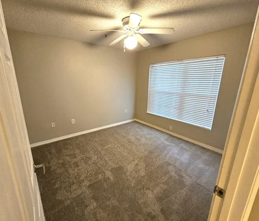 an empty room with windows and fan