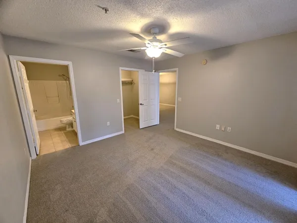 an empty room with closet and a ceiling fan