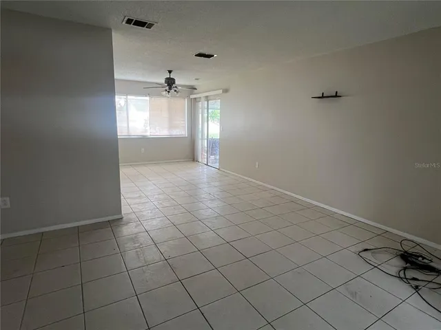 an empty room with windows and ceiling fan