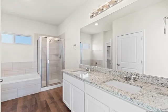 a bathroom with a granite countertop double vanity sink and mirror