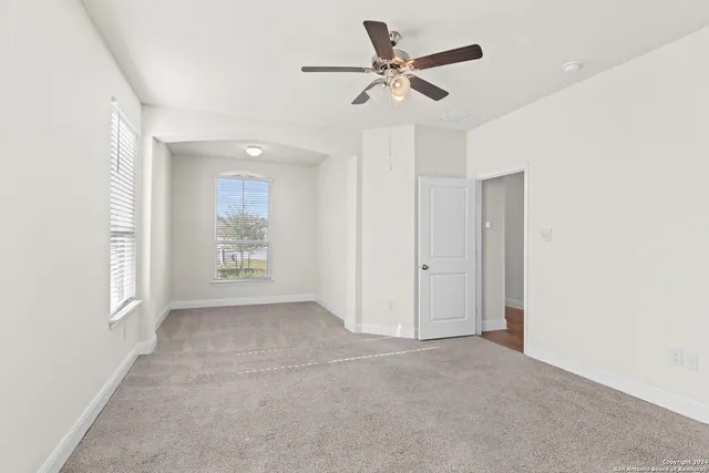 an empty room with windows and fan