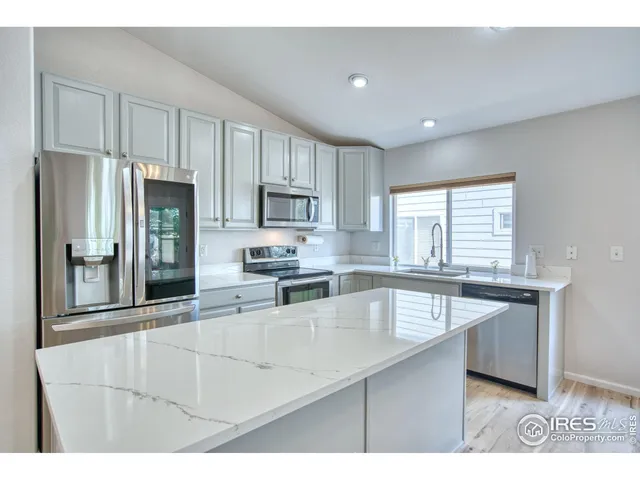 a kitchen with stainless steel appliances granite countertop a stove a sink a refrigerator and white cabinets
