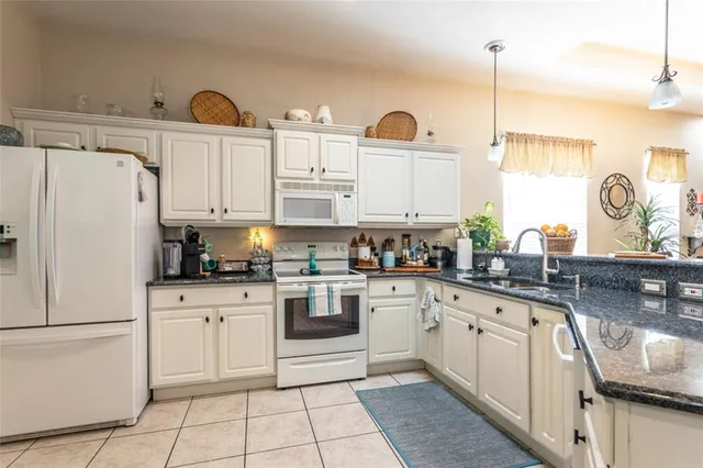 a kitchen with granite countertop white cabinets and white appliances