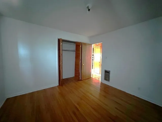 an empty room with wooden floor and closet