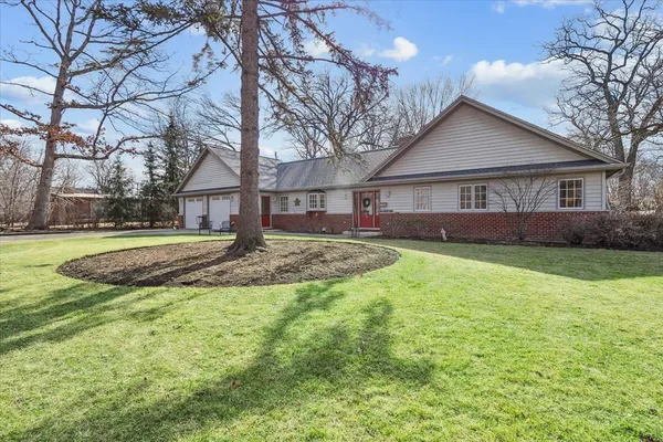 a view of house with a big yard potted plants and large tree