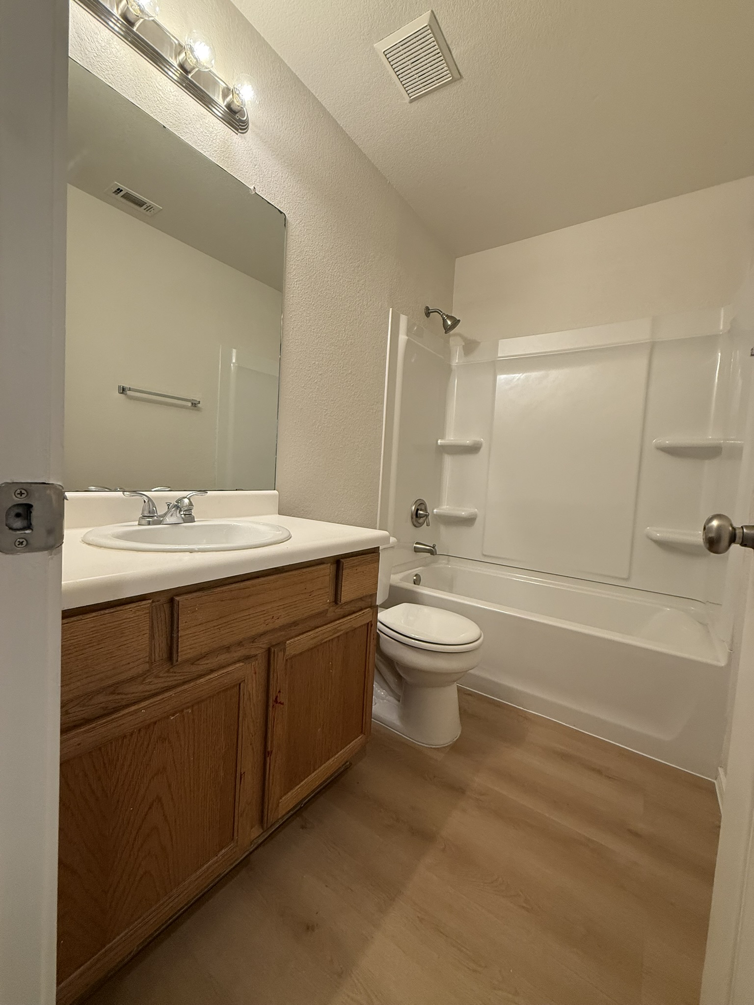 1209 Armadillo Road, Unit A Austin, TX 78745 - Photo 10 of 15 Full bath with vanity, light wood finished floors, a textured wall, washtub / shower combination, and a textured ceiling