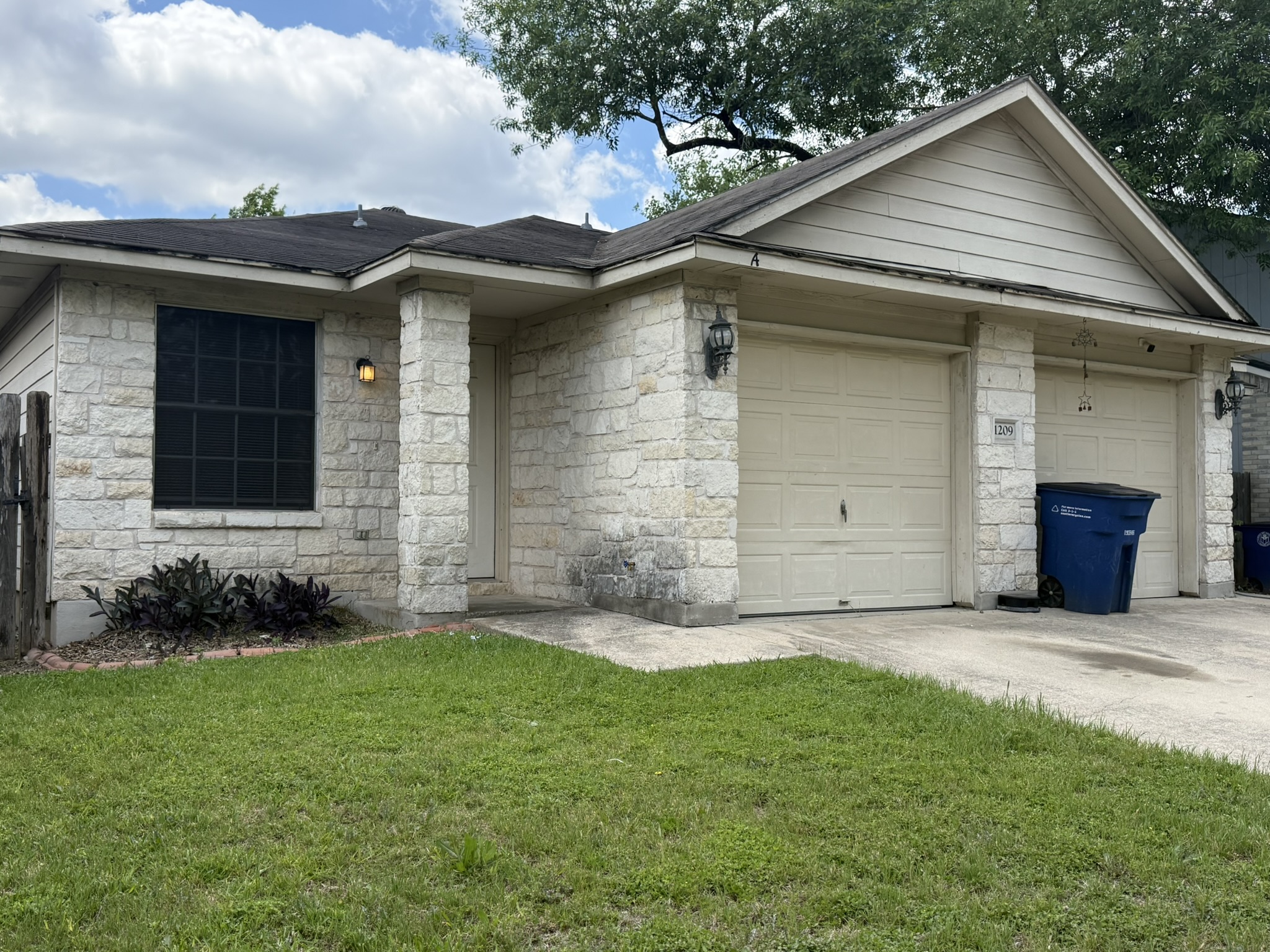 1209 Armadillo Road, Unit A Austin, TX 78745 - Photo 2 of 15 View of front of house with a garage, a front yard, stone siding, and concrete driveway