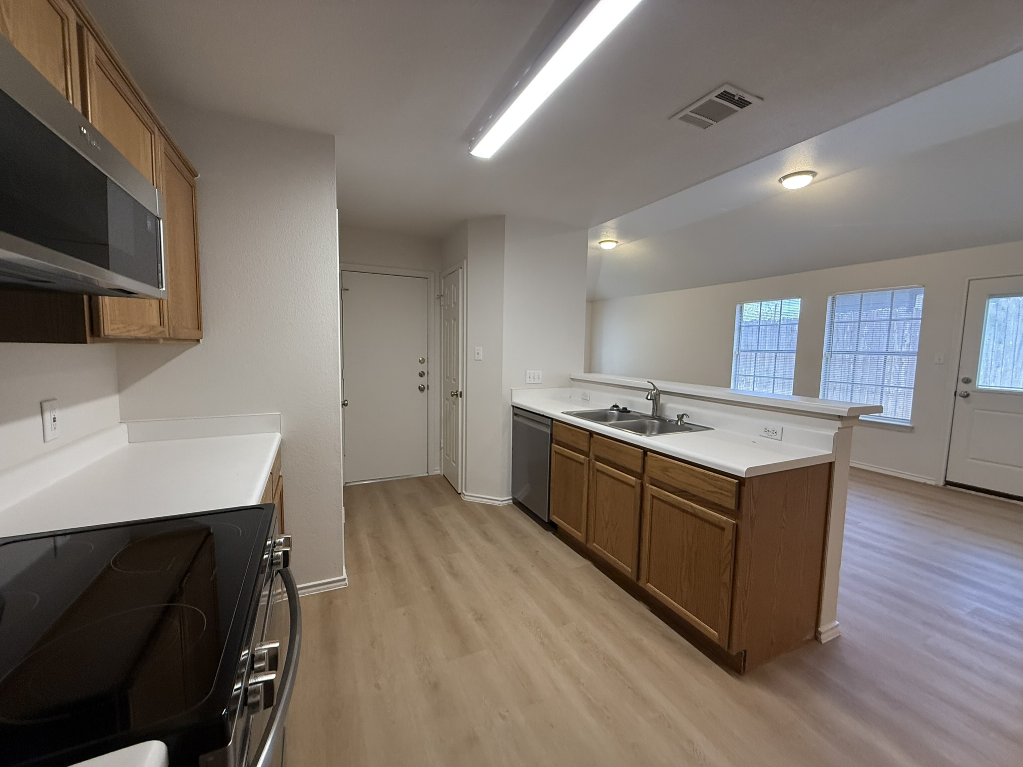 1209 Armadillo Road, Unit A Austin, TX 78745 - Photo 8 of 15 Kitchen with stainless steel appliances, light countertops, a peninsula, light wood-style floors, and wood finish cabinetry