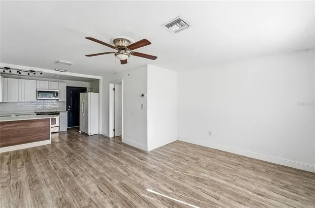 a view of a room with wooden floor and a ceiling fan