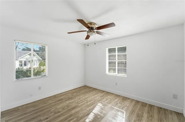 a view of empty room with wooden floor and fan