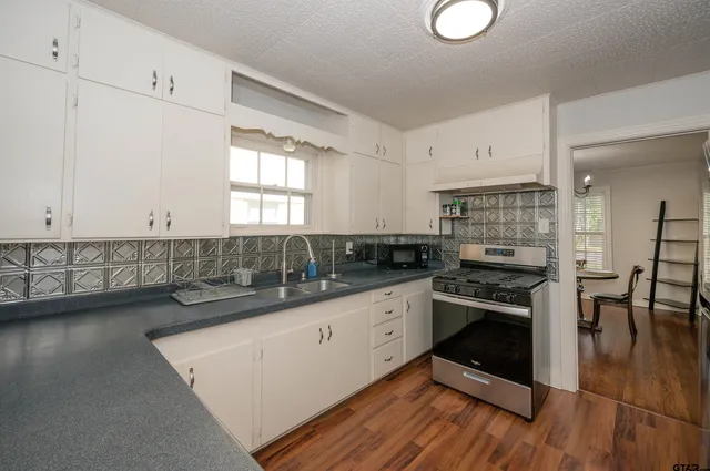a kitchen with granite countertop a stove a sink and a refrigerator