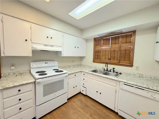 a kitchen with granite countertop white cabinets and white appliances