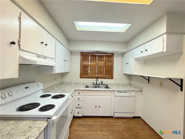 a kitchen that has a sink a stove and cabinets in it