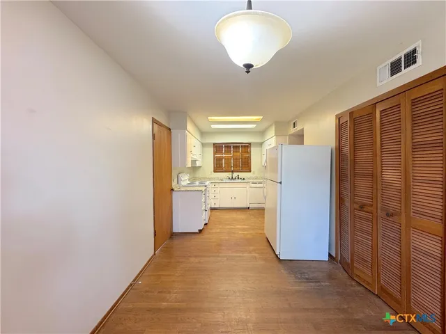 a view of kitchen with refrigerator cabinets and wooden floor