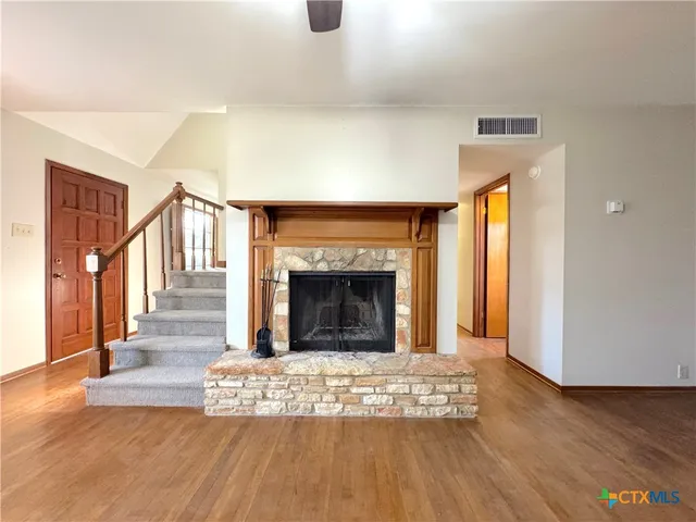 a view of an empty room with wooden floor fireplace and a window