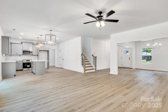 a view of an empty room with wooden floor and a ceiling fan